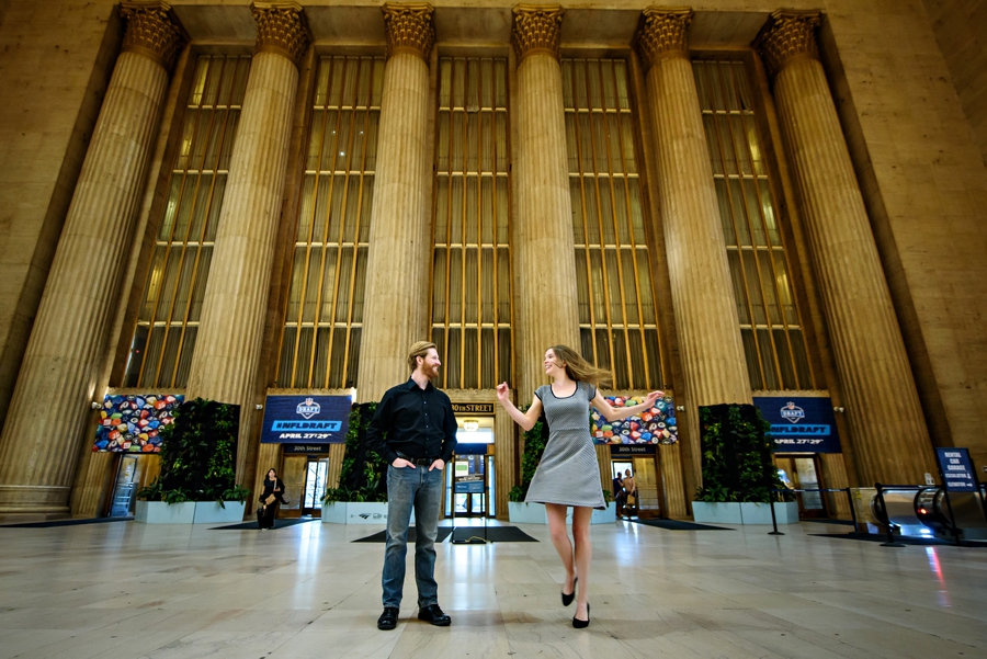 An engaged couple dance in front of the columns inside 30th street station during their philadelphia engagement session.